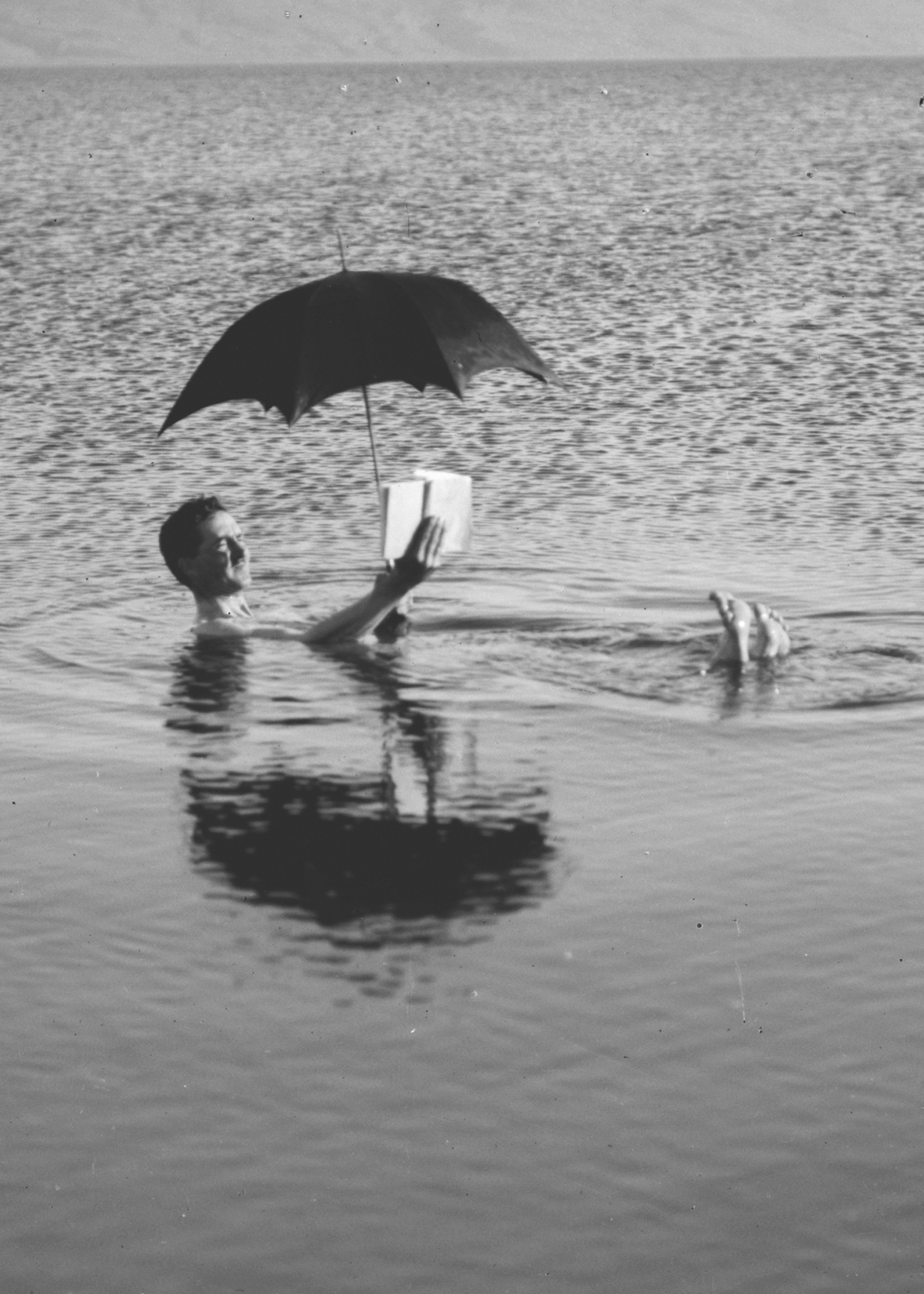 A man floating and reading under an umbrella in 1930, when the Rivierenbuurt in Amsterdam was first established.
